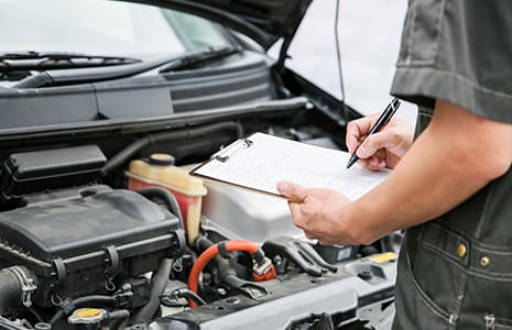 An inspector recording a vehicle's details on a checklist in Japan
