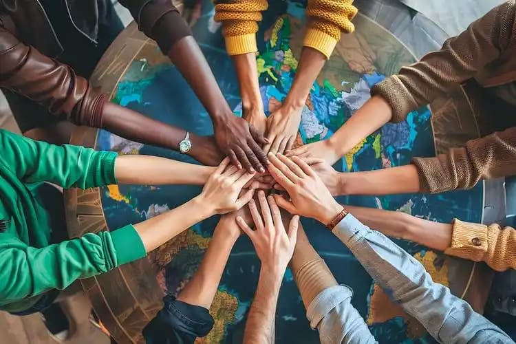 Hands of people from many countries joined over a world map